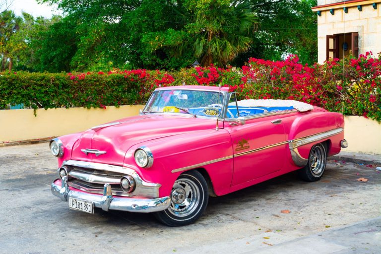 A pink old fashioned car.